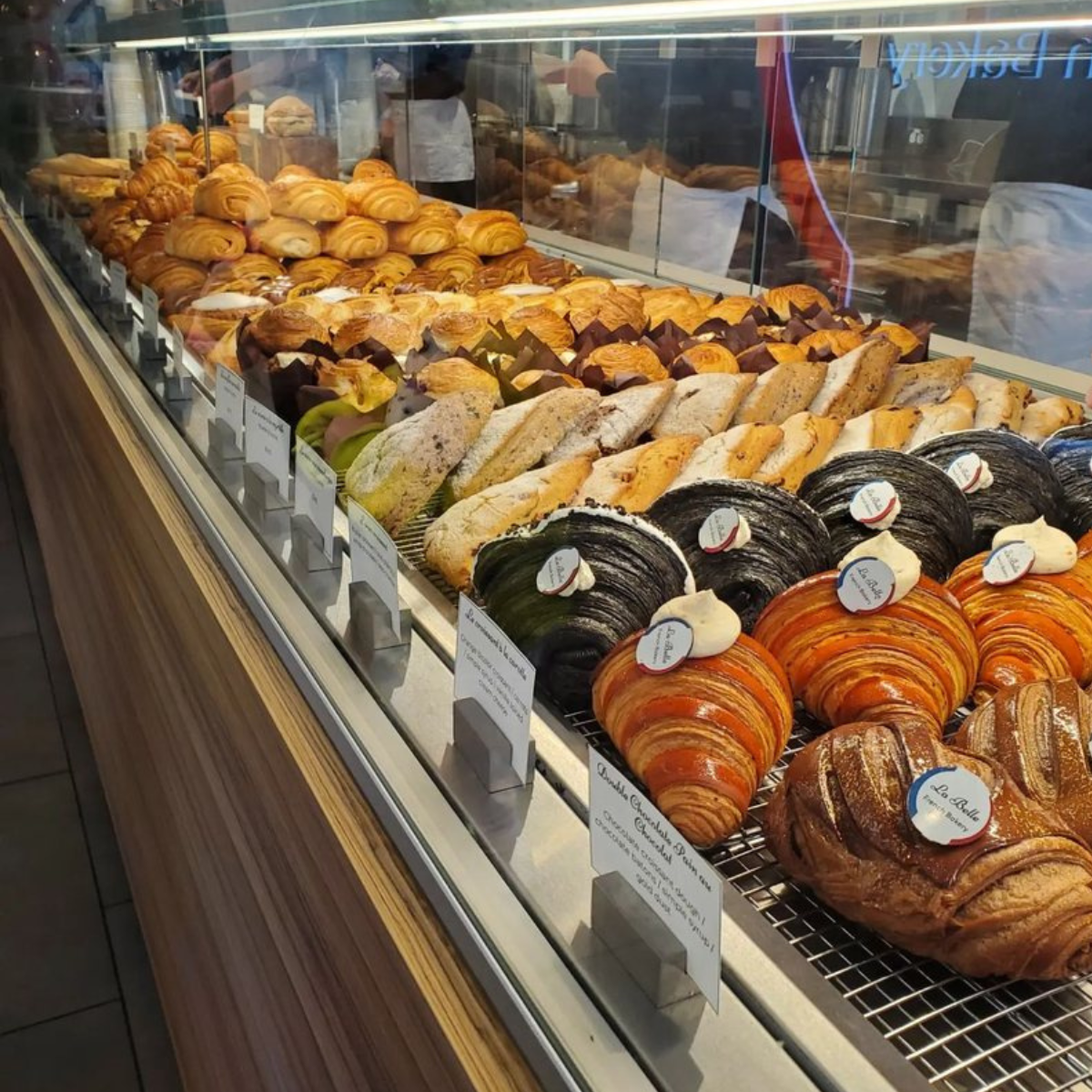 Close Up of straight glass bakery display with rows of croissants and pastry inside.